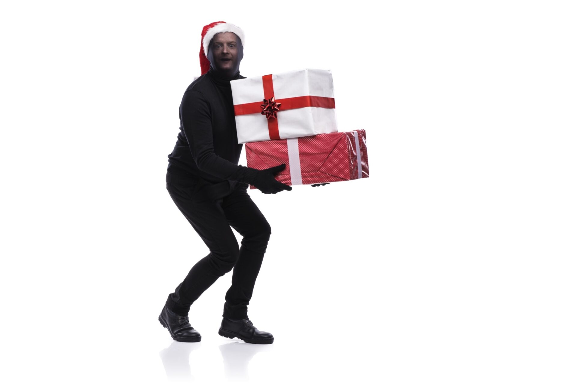 Thief in black mask - stock photo Thief in action carrying presents with balaclava on his face, dressed in black. Studio shot on white background.